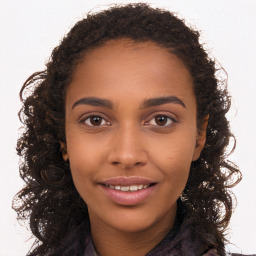 Joyful black young-adult female with long  brown hair and brown eyes