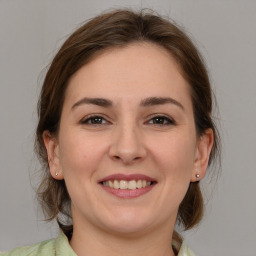 Joyful white young-adult female with medium  brown hair and grey eyes