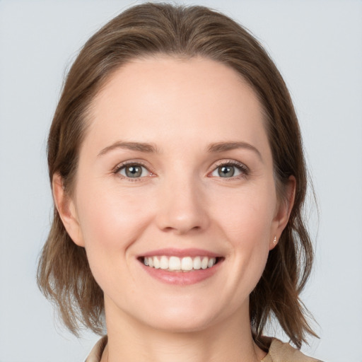 Joyful white young-adult female with medium  brown hair and grey eyes