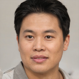 Joyful asian young-adult male with short  brown hair and brown eyes