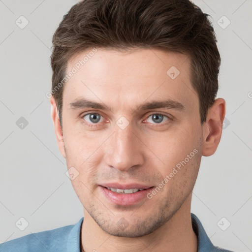 Joyful white young-adult male with short  brown hair and grey eyes