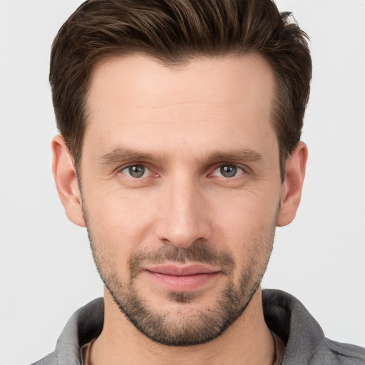 Joyful white young-adult male with short  brown hair and grey eyes