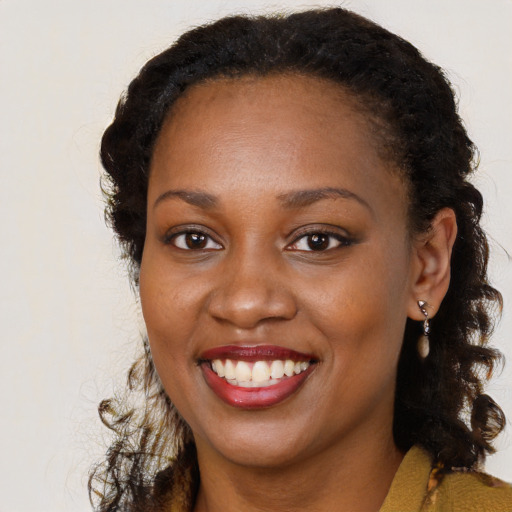 Joyful black young-adult female with long  brown hair and brown eyes