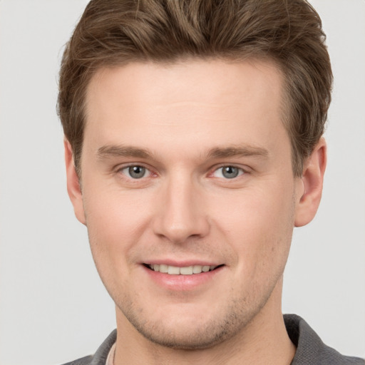 Joyful white young-adult male with short  brown hair and grey eyes