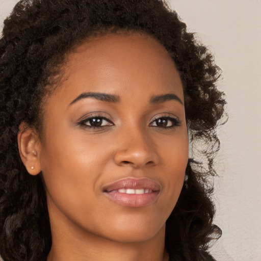 Joyful black young-adult female with long  brown hair and brown eyes