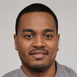 Joyful black young-adult male with short  black hair and brown eyes