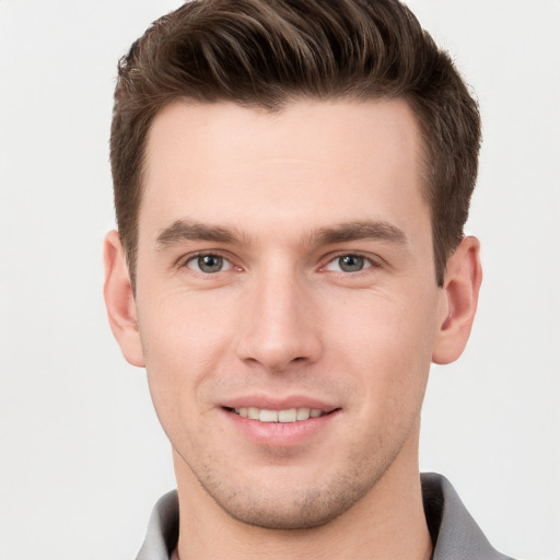 Joyful white young-adult male with short  brown hair and grey eyes