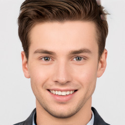 Joyful white young-adult male with short  brown hair and grey eyes