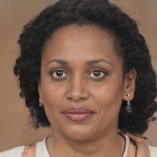 Joyful black adult female with long  brown hair and brown eyes