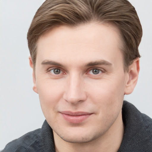 Joyful white young-adult male with short  brown hair and grey eyes