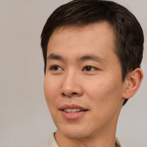 Joyful asian young-adult male with short  brown hair and brown eyes