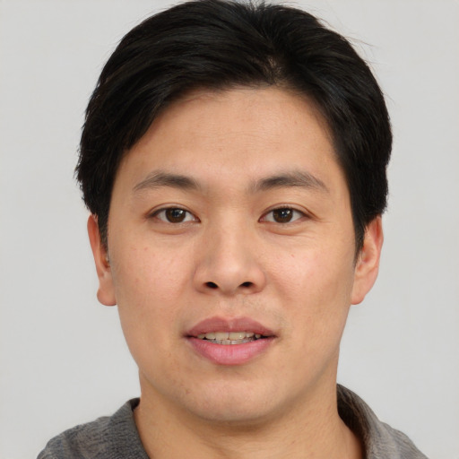 Joyful asian young-adult male with short  brown hair and brown eyes