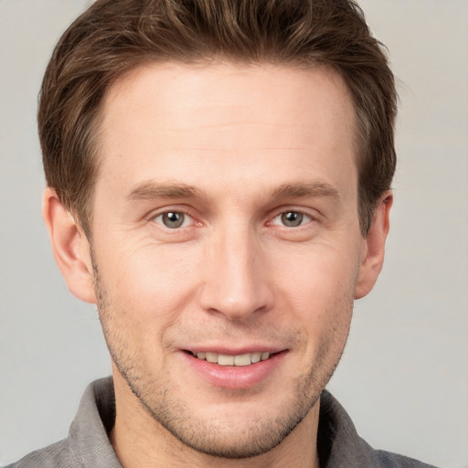 Joyful white young-adult male with short  brown hair and grey eyes