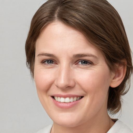 Joyful white young-adult female with medium  brown hair and grey eyes