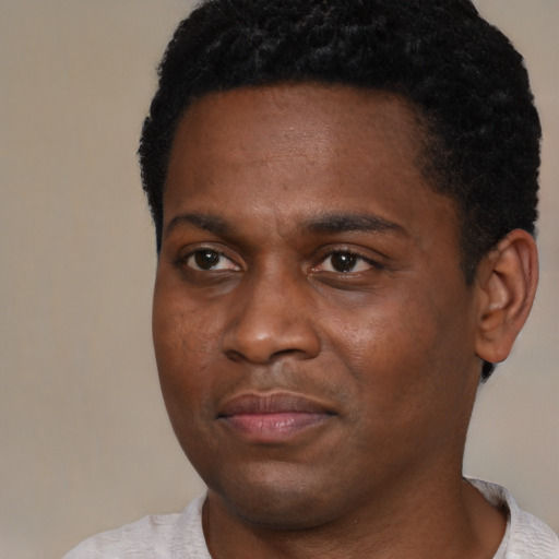 Joyful black young-adult male with short  black hair and brown eyes