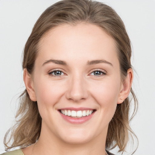 Joyful white young-adult female with medium  brown hair and grey eyes