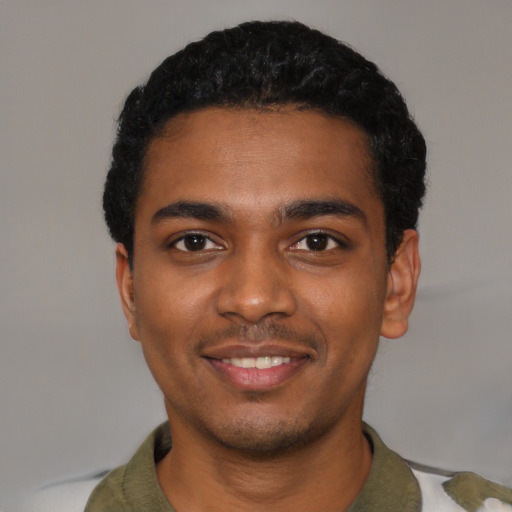 Joyful black young-adult male with short  black hair and brown eyes