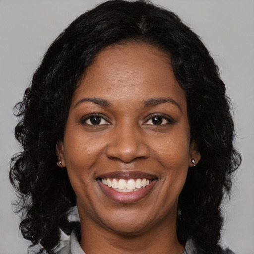 Joyful black young-adult female with long  black hair and brown eyes