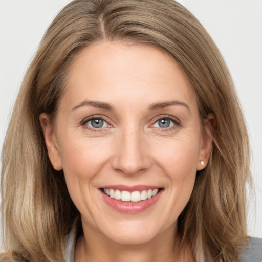 Joyful white adult female with long  brown hair and grey eyes