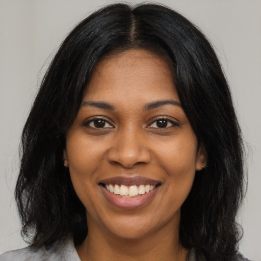 Joyful black young-adult female with long  black hair and brown eyes
