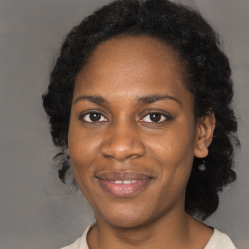 Joyful black young-adult female with long  black hair and brown eyes