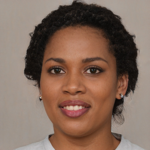 Joyful black young-adult female with short  black hair and brown eyes