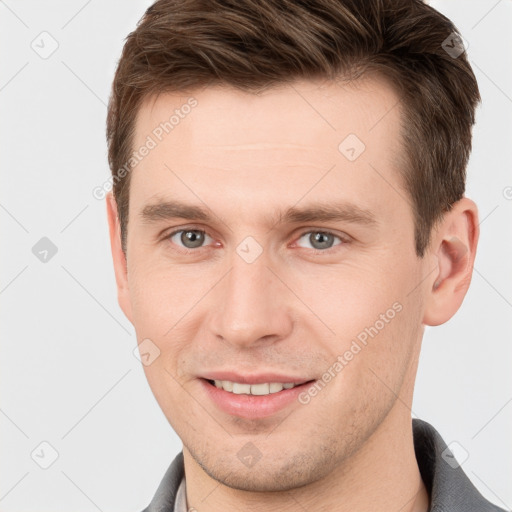 Joyful white young-adult male with short  brown hair and grey eyes