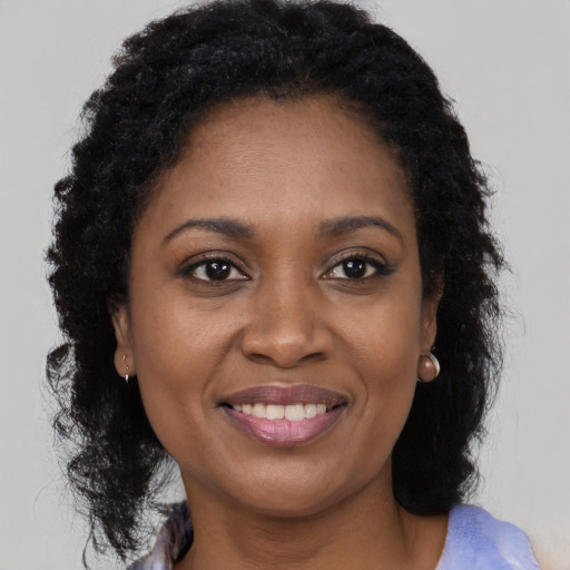 Joyful black young-adult female with long  brown hair and brown eyes