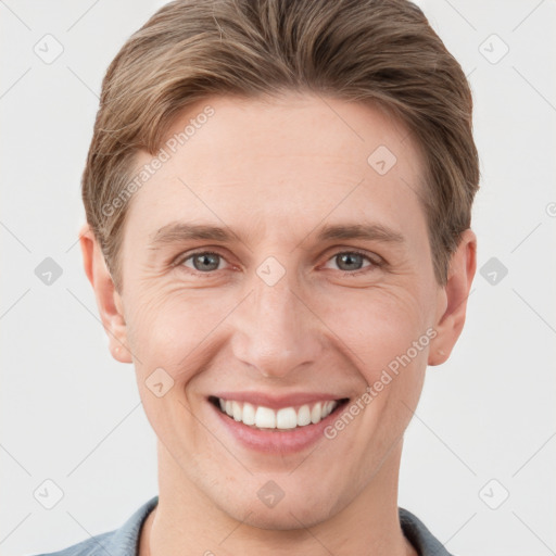 Joyful white young-adult male with short  brown hair and grey eyes