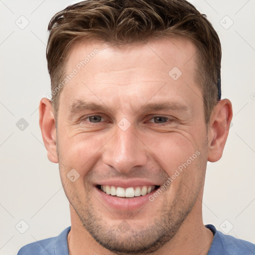 Joyful white adult male with short  brown hair and grey eyes