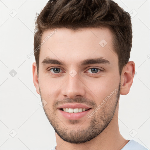 Joyful white young-adult male with short  brown hair and grey eyes