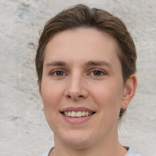 Joyful white young-adult female with short  brown hair and grey eyes