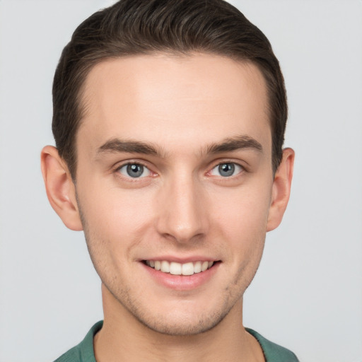 Joyful white young-adult male with short  brown hair and grey eyes