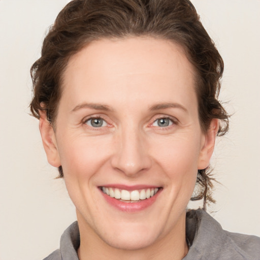 Joyful white adult female with medium  brown hair and grey eyes