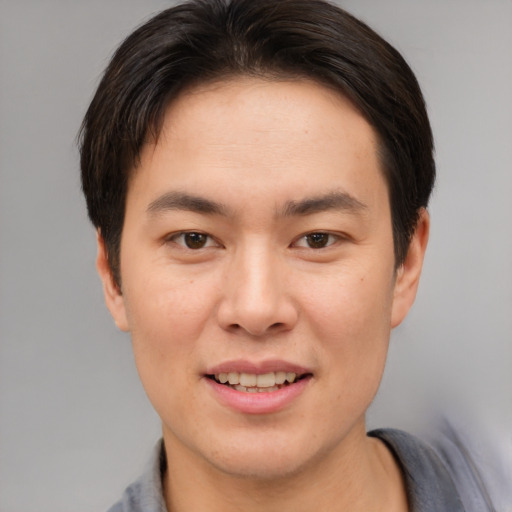 Joyful asian young-adult male with short  brown hair and brown eyes