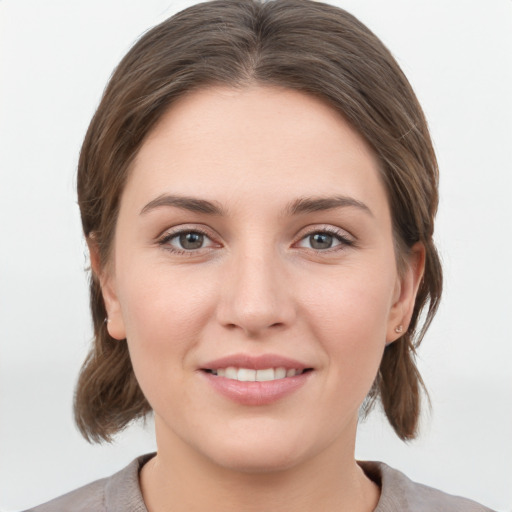 Joyful white young-adult female with medium  brown hair and grey eyes