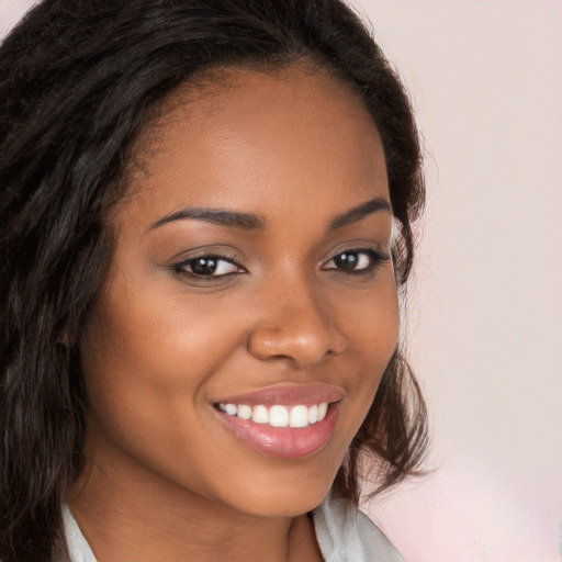 Joyful black young-adult female with long  brown hair and brown eyes