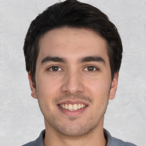 Joyful white young-adult male with short  black hair and brown eyes