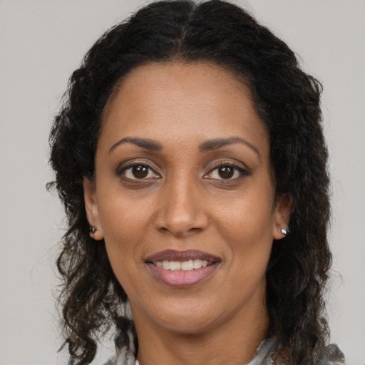 Joyful black adult female with long  brown hair and brown eyes