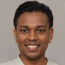 Joyful black young-adult male with short  black hair and brown eyes