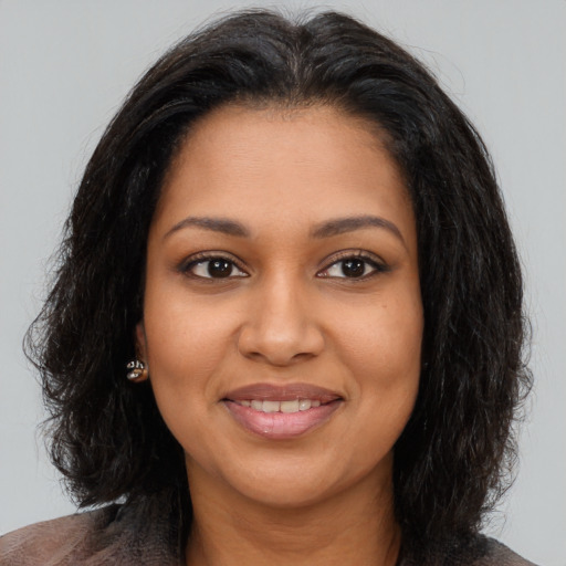 Joyful black young-adult female with long  brown hair and brown eyes