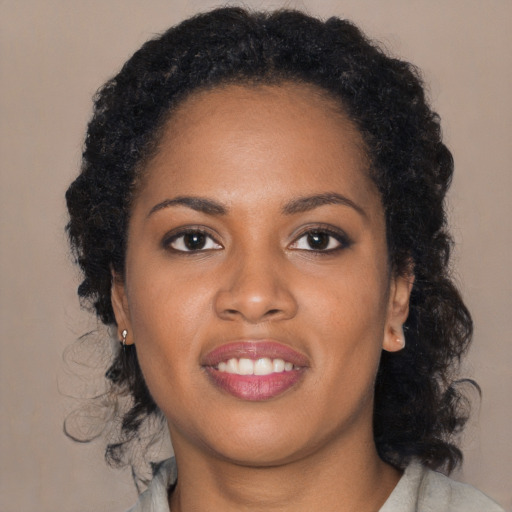 Joyful black young-adult female with long  brown hair and brown eyes