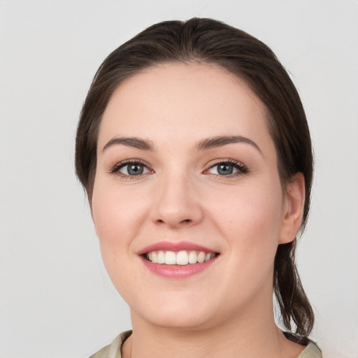 Joyful white young-adult female with medium  brown hair and grey eyes