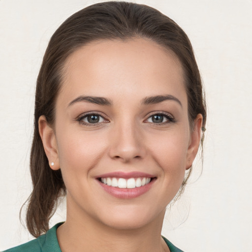 Joyful white young-adult female with medium  brown hair and grey eyes