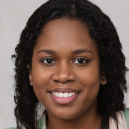 Joyful black young-adult female with long  brown hair and brown eyes