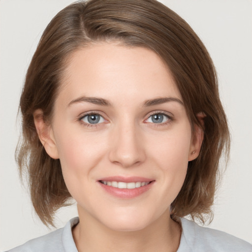 Joyful white young-adult female with medium  brown hair and grey eyes