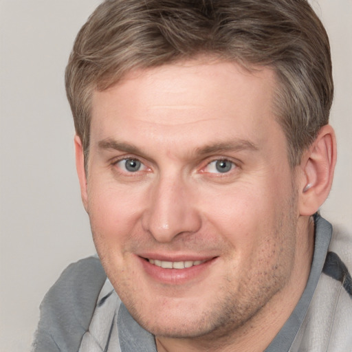 Joyful white adult male with short  brown hair and grey eyes