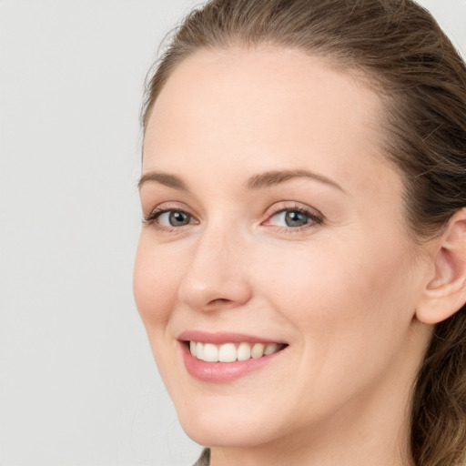 Joyful white young-adult female with long  brown hair and blue eyes