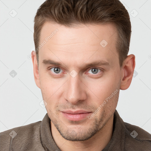 Joyful white young-adult male with short  brown hair and grey eyes