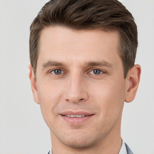 Joyful white young-adult male with short  brown hair and grey eyes